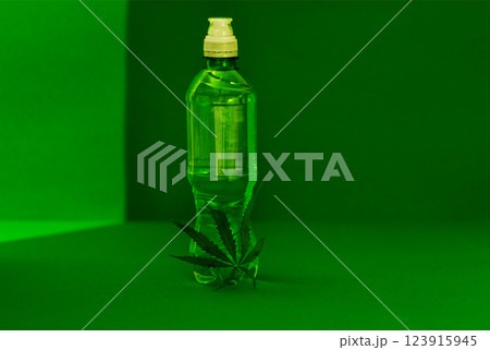 A mock-up of a transparent plastic bottle with a white lid with pure mineral water and a green cannabis leaf. Bottle layout and hemp. A mock-up of a transparent plastic bottle with a white lid with pure mineral water and a green cannabis leaf. Bottle layout and hemp. 123915945