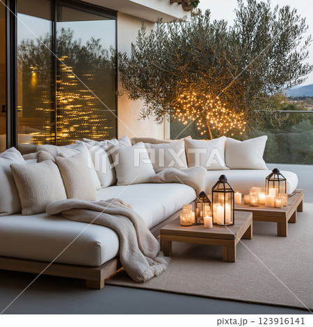 Cozy outdoor lounge with white cushions, lanterns, and warm lighting at dusk 123916141