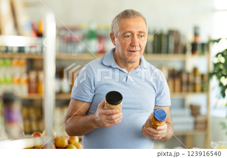 Elderly man chooses beans at grocery store 123916540