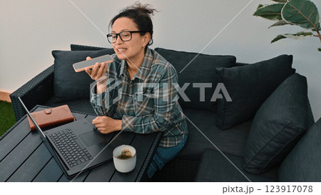 Woman Working Remotely While Talking on Smartphone in Outdoor Setting Woman Working Remotely While Talking on Smartphone in Outdoor Setting 123917078