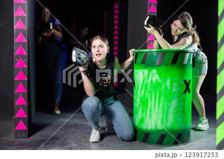 Portrait of excited girlfriends playing enthusiastically laser tag game two teams opposite each other in room Portrait of excited girlfriends playing enthusiastically laser tag game two teams opposite each other in room 123917253