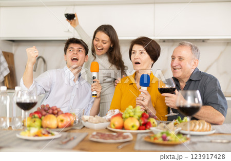 Joyful family singing at home karaoke during festive gathering Joyful family singing at home karaoke during festive gathering 123917428