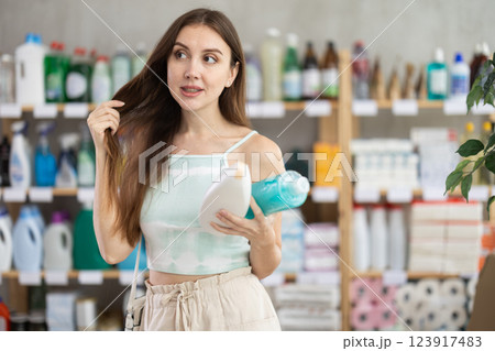 Woman looking for trademark sign on label, chooses eco friendly shampoo or shower gel 123917483
