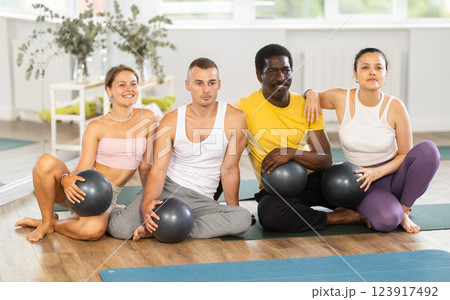 Yoga and Pilates teacher poses with multinational students after fitball session in studio Yoga and Pilates teacher poses with multinational students after fitball session in studio 123917492