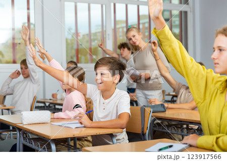 School pupils raise their hands up in classroom 123917566