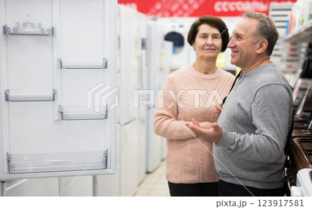 Middle aged wife and husband picking new refrigerator in store Middle aged wife and husband picking new refrigerator in store 123917581