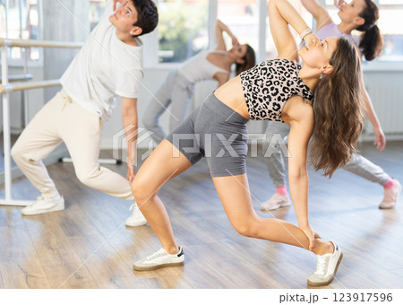 Young girl practicing hip-hop dance in training hall in group Young girl practicing hip-hop dance in training hall in group 123917596