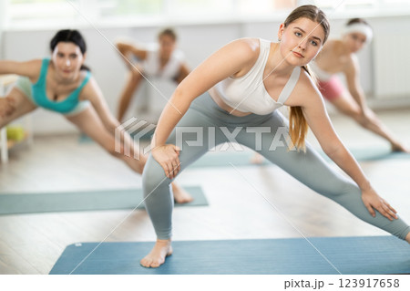 Group of young women doing stretching in studio Group of young women doing stretching in studio 123917658