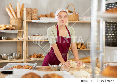 Young female baker kneading dough on table Young female baker kneading dough on table 123917677