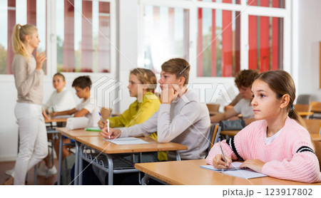 Teenagers sitting at desks in classroom during lesson Teenagers sitting at desks in classroom during lesson 123917802