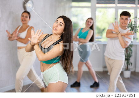 Girl teen perform choreographic exercise and teach energetic mobile social dance groove with friends Girl teen perform choreographic exercise and teach energetic mobile social dance groove with friends 123917851