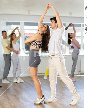 Group of multiethnic active sports girl and guy dancing social dance movements in studio 123917870