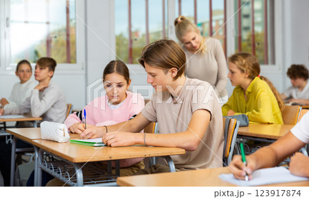 Teenagers sitting at desks in classroom during lesson 123917874