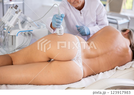 Cosmetologist using cold hammer for hardware procedure on buttocks of woman Cosmetologist using cold hammer for hardware procedure on buttocks of woman 123917983