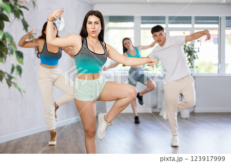 Expressive Hispanic teenage girl dancing hip-hop with group in studio 123917999