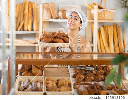 Young saleswoman displays croissants in square wicker basket Young saleswoman displays croissants in square wicker basket 123918106