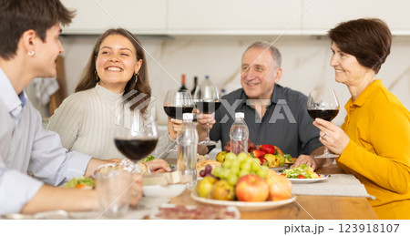 Father and mother together with adult children talking at dinner table at home Father and mother together with adult children talking at dinner table at home 123918107