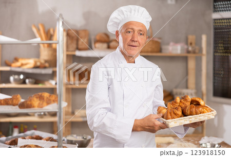 Elderly male baker with basket of croissants Elderly male baker with basket of croissants 123918150