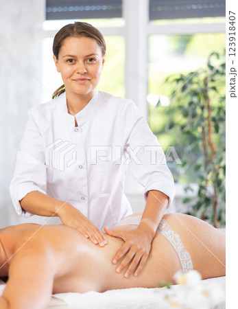 Professional young female massage therapist doing back massage to woman 123918407