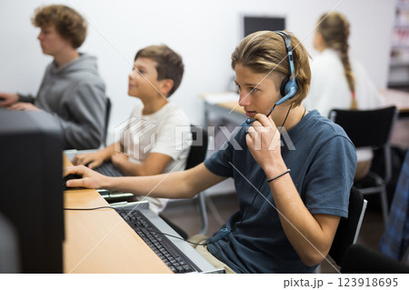Portrait of a fifteen-year-old schoolboy in headphones at a computer Portrait of a fifteen-year-old schoolboy in headphones at a computer 123918695
