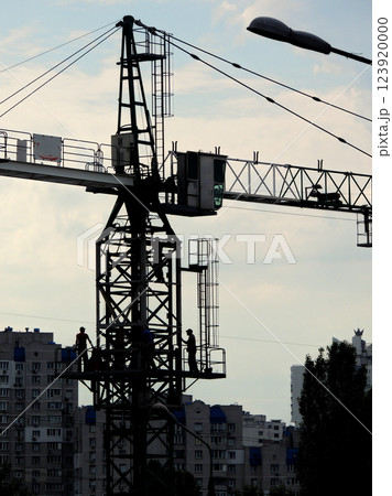 Cabin Of Tower Crane With Workers Silhouettes Over Construction Site 123920000