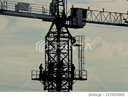Silhouettes Of Workers On A Tower Crane At Works  123920002