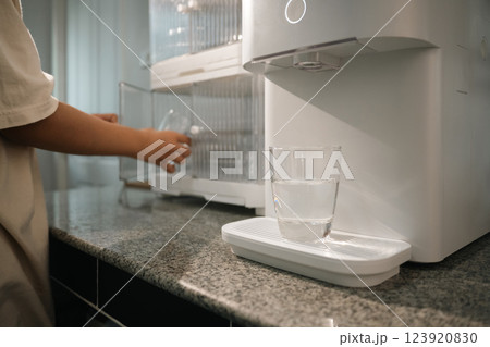 A transparent glass filled with filtered water from a high tech water purifier on kitchen counter 123920830