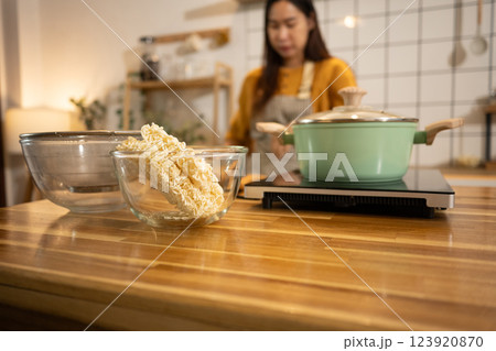 Glass bowl filled with dry instant noodles on a wooden countertop, ready to be cooked 123920870