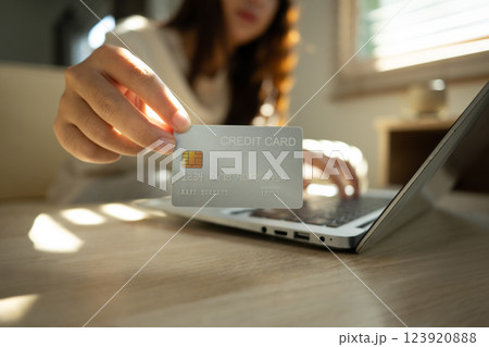 Woman showing a credit card while using a laptop, digital transactions and online shopping concept 123920888