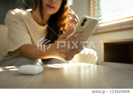 Close up shot of smiling woman connecting wireless earbuds to smartphone 123920908