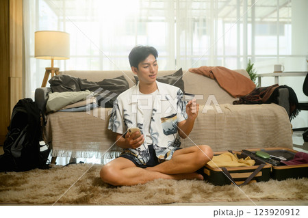 Man holding credit card booking flights and accommodations on mobile phone for summer trip Man holding credit card booking flights and accommodations on mobile phone for summer trip 123920912