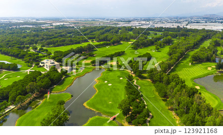 Panoramic aerial view of a golf course with ponds, sand bunkers, and a clubhouse surrounded by nature 123921168