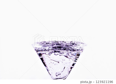 Close-up of water drop falling into a glass on white background Close-up of water drop falling into a glass on white background 123921196