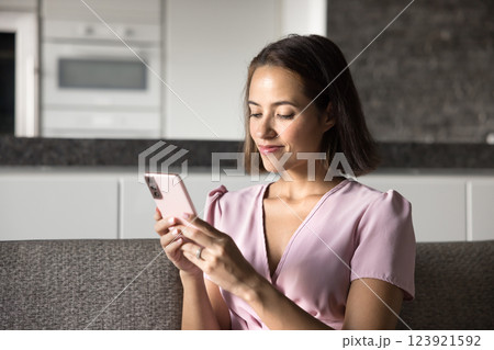 Young woman holding her smartphone seated on couch at home 123921592