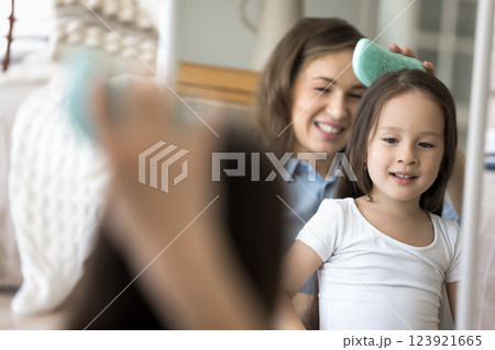 Mirror reflection loving young mother combing daughter hair with brush 123921665