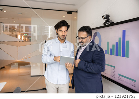 Young Latin employee showing electronic report to elder boss 123921755