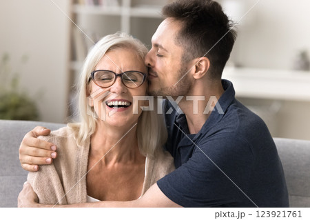 Grateful young son embrace kiss in temple smiling retired mother 123921761