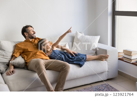 Joyful man and little daughter relaxing on white, comfortable couch Joyful man and little daughter relaxing on white, comfortable couch 123921764