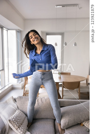 Happy Indian woman dancing jumping on sofa at home Happy Indian woman dancing jumping on sofa at home 123921879