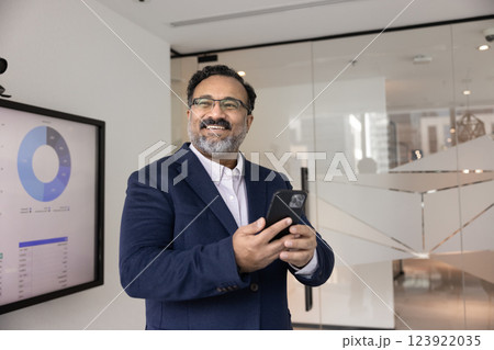 Cheerful mature Indian company director man using modern technology 123922035