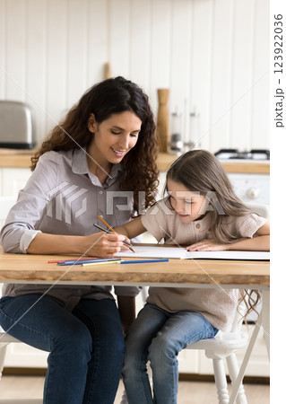 Happy millennial mother young daughter painting pictures at coloring book Happy millennial mother young daughter painting pictures at coloring book 123922036