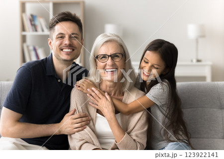 Mature female grownup son preteen age granddaughter hugging on couch Mature female grownup son preteen age granddaughter hugging on couch 123922141