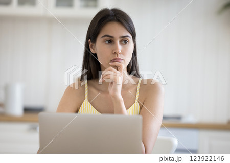 Young lady distracted from work on notebook with pensive look Young lady distracted from work on notebook with pensive look 123922146
