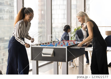 Two multiethnic women colleagues playing foosball game Two multiethnic women colleagues playing foosball game 123922177