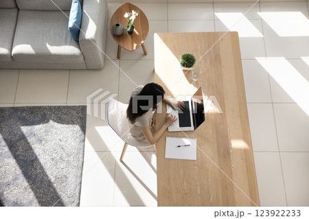 Woman working on laptop seated at table, overhead view Woman working on laptop seated at table, overhead view 123922233