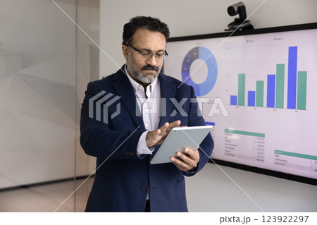 Serious senior Indian business leader man analyzing marketing data Serious senior Indian business leader man analyzing marketing data 123922297