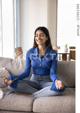 Woman do meditation practice seated in lotus position on couch Woman do meditation practice seated in lotus position on couch 123922368