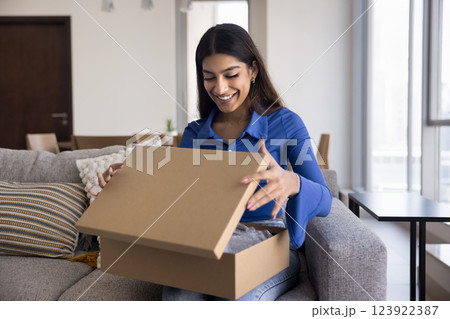 Woman opening cardboard box, feel satisfied with express delivery services Woman opening cardboard box, feel satisfied with express delivery services 123922387