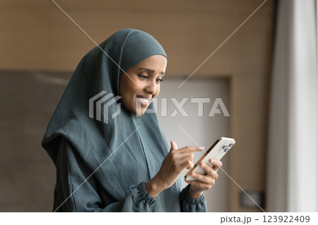 Woman in traditional abaya using smartphone at workplace 123922409