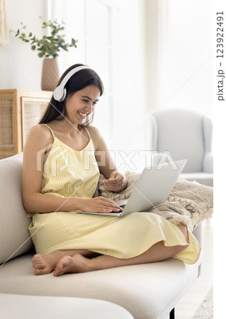 Cheerful young female wearing headphones chatting by videocall on notebook 123922491
